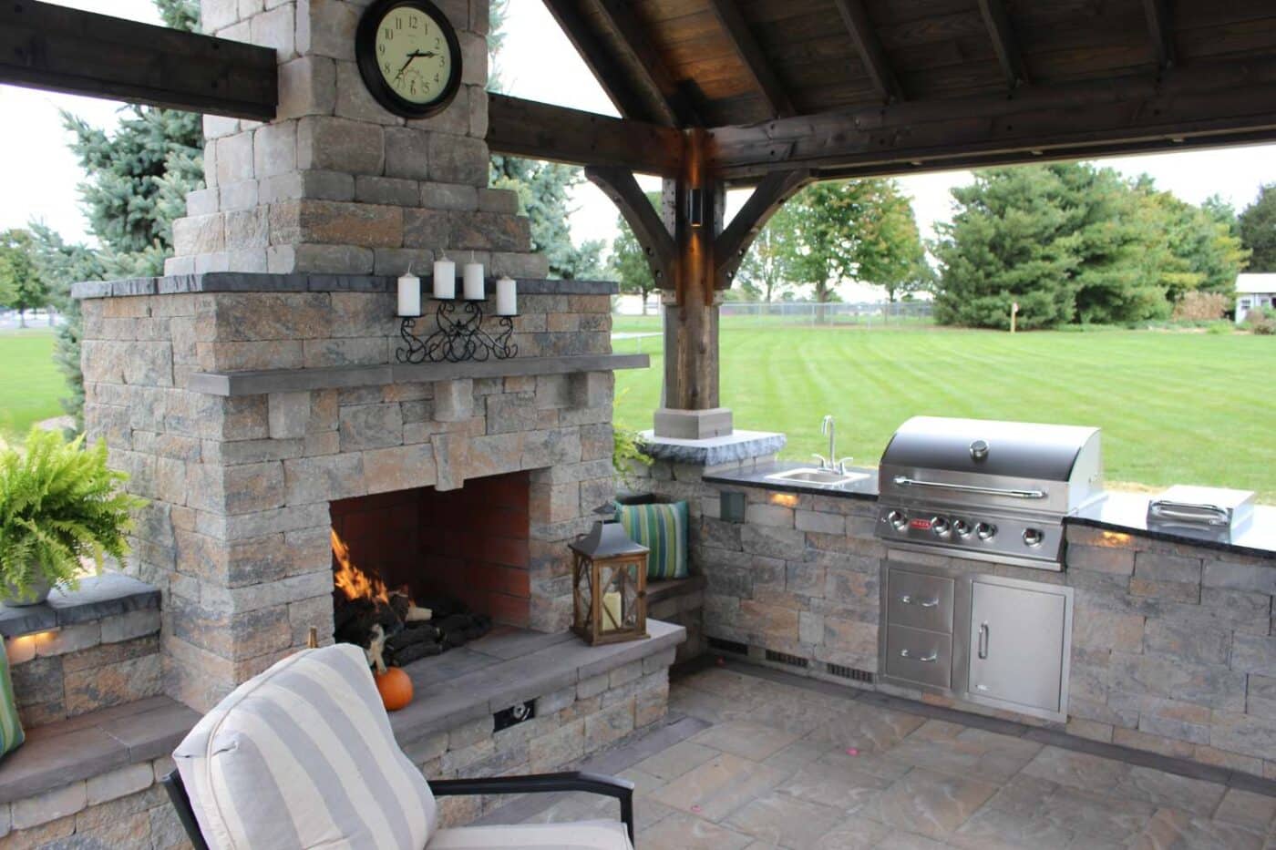 Outdoor kitchen with grill, sink, and fireplace