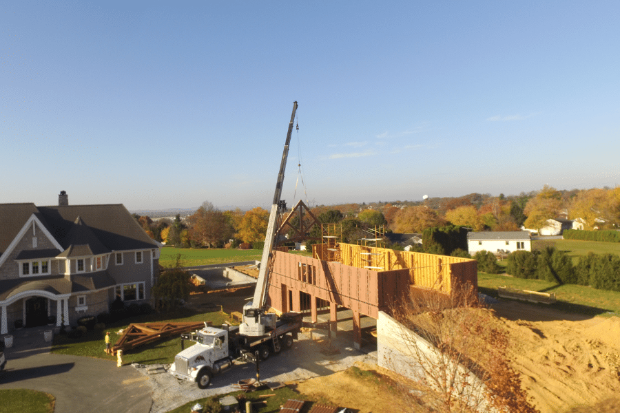 crane lowering roof truss onto frame of barn/pool entertainment center