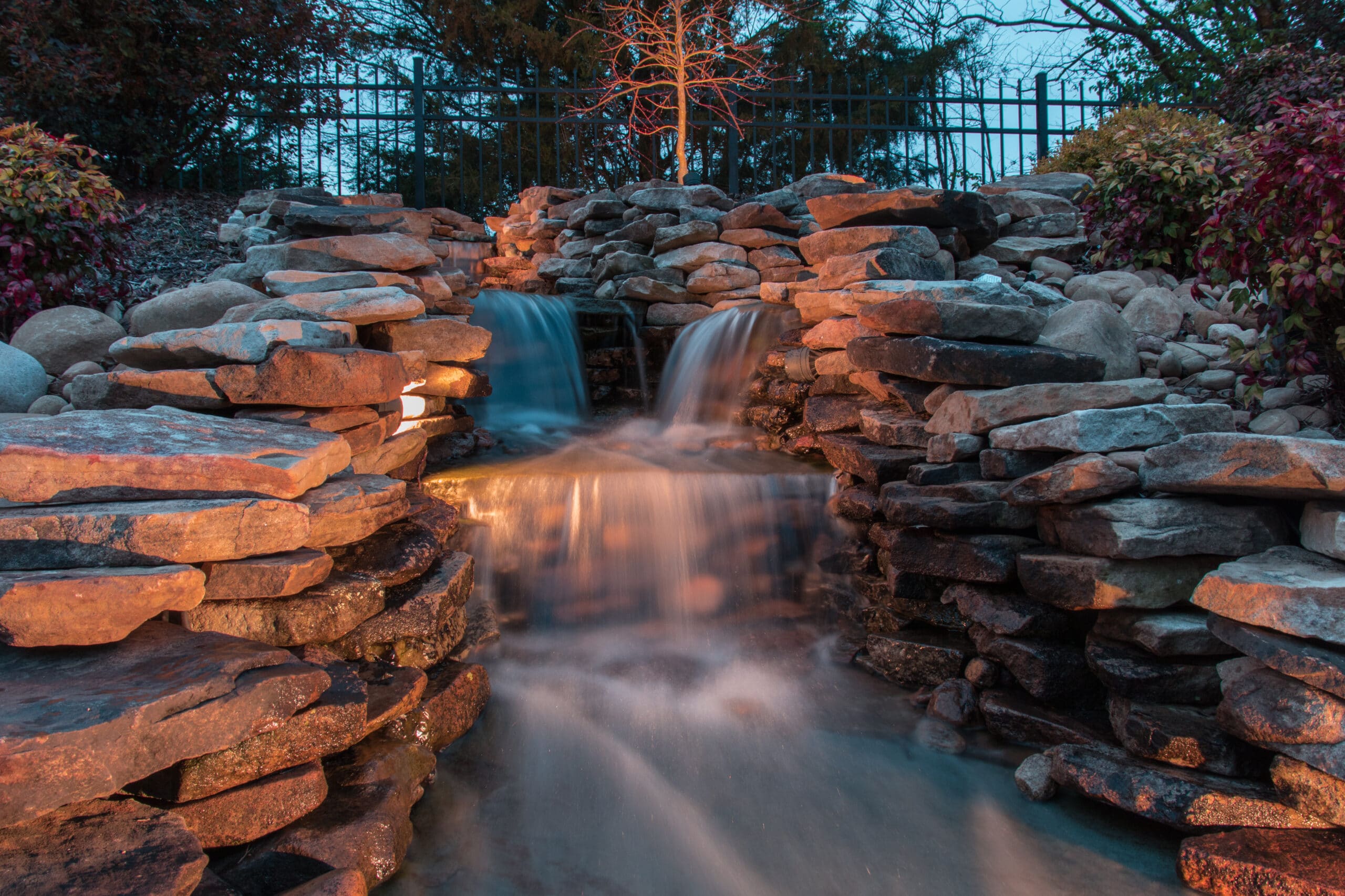 beautiful long exposure of backyard cascading waterfall and landscaping for peaceful ambiance