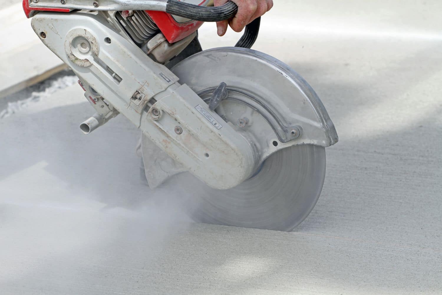 Hand holding a working saw cutting concrete which could lead to silica dust in home environments.