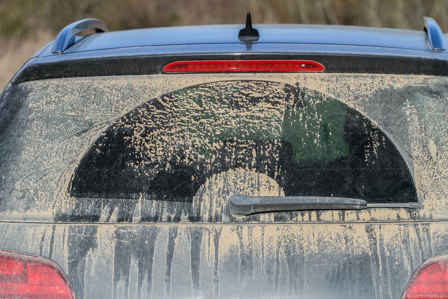 rear window of dusty car covered partially wiped with windshield wiper in silica dust - could lead to tacking silica dust in home areas